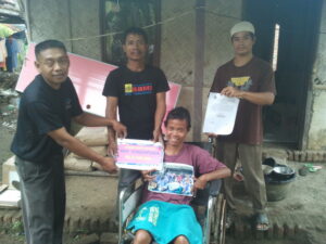 Rokiyah (duduk di kursi roda) menerima bantuan dari perkumpulan BMI Singapura. Bantuan diserahkan secara simbolik oleh perwakilan-perwakilan dari DPC SBMI Indramayu.